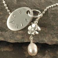 A sweet little gift for the flower girl. Thick oval sterling silver disc with name stamped around the edge Sterling silver flower bead with freshwater pearl attached Includes 16" sterling silver ball chain necklace This necklace is CPSIA compliant as shown Makes a great gift idea for a flower girl, special little godchild or daughter, niece or cousin.