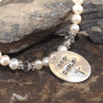    Sterling silver hand stamped oval that says God Child with a cross   Creamy White Freshwater Pearls   Sterling silver beads and accents   Includes grow chain